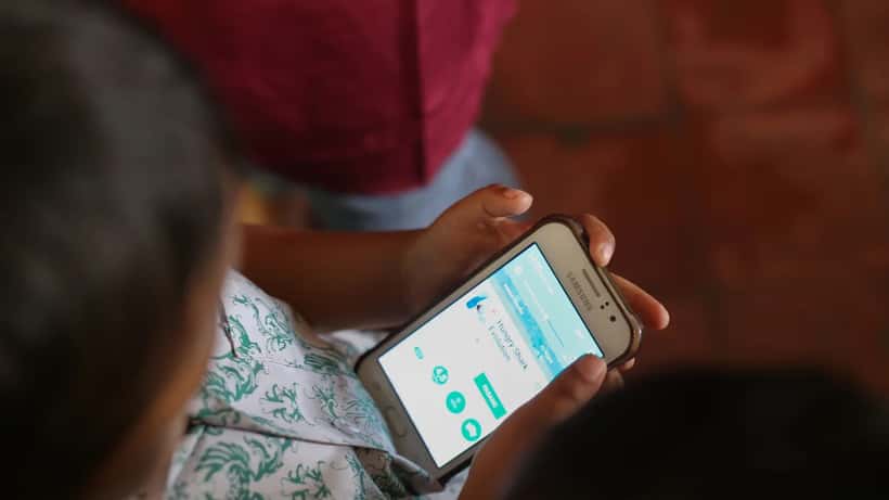 Criança usando smartphone para baixar jogo mobile, representando o impacto da lei de loot boxes para menores no Brasil