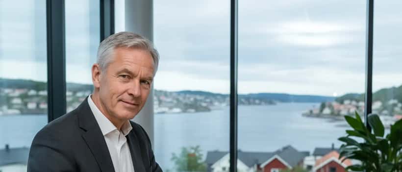 Norsk mann i dress gjennomgår finansdokumenter i Oslo-kontor med fjordutsikt
