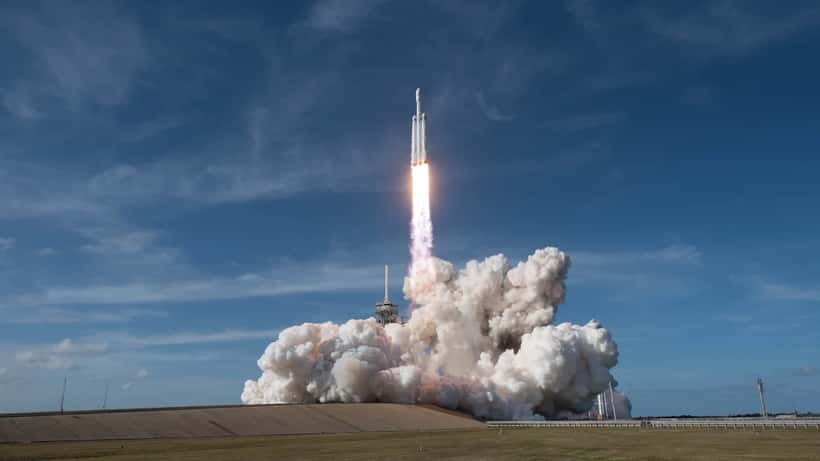 SpaceX Falcon Heavy rocket launching from Kennedy Space Center against blue sky