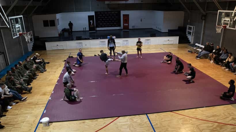 Mixed martial artists demonstrating grappling techniques at a live event for troops