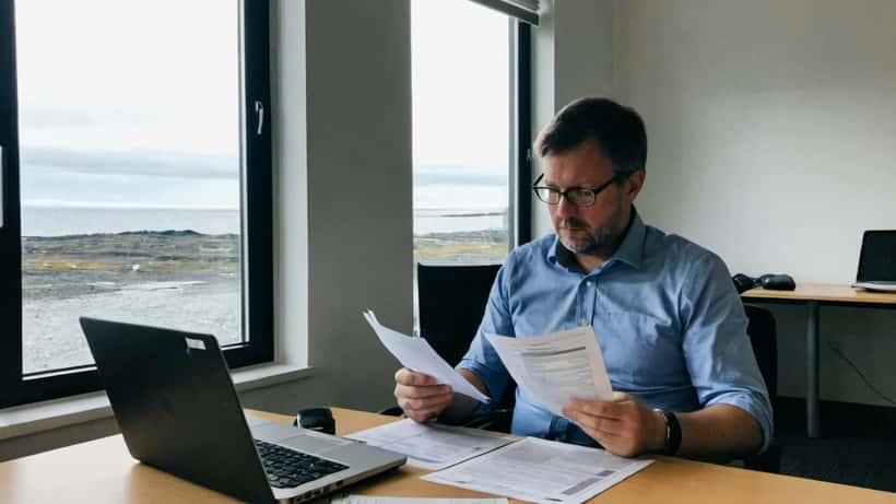 IT-sérfræðingur fer yfir EU AI Act skjöl á skrifborði í Reykjavík skrifstofu