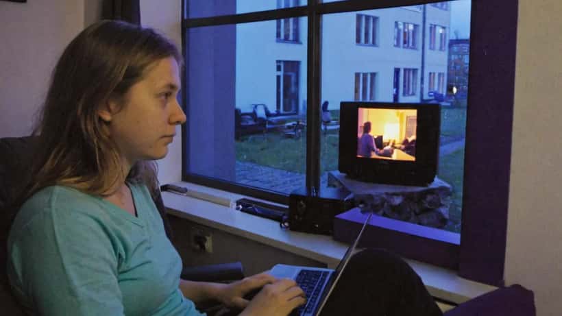 Kvinde ser serie på skærm i lejlighed om aftenen, blå TV-lys i baggrunden