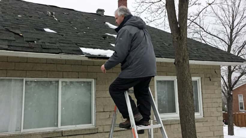 Canadian homeowner inspecting roof damage after a spring snowstorm