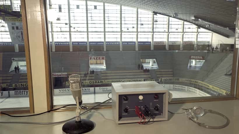 Sportkommentatorsbås vid en ishockeyarena med mikrofon och teknikutrustning