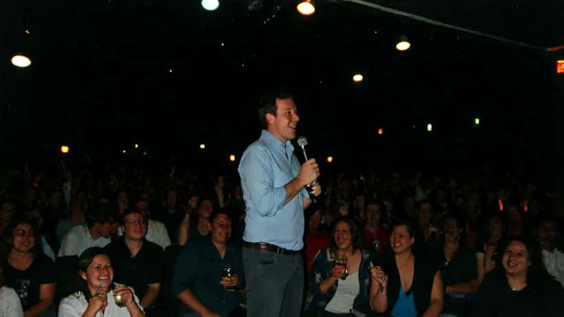 Stand-up comedian performing on stage under spotlight with laughing audience at Sydney comedy club