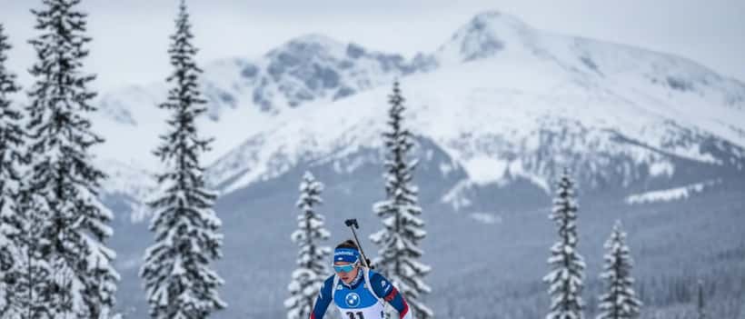 Biathlète féminine en compétition dans un paysage nordique enneigé, fusil dans le dos