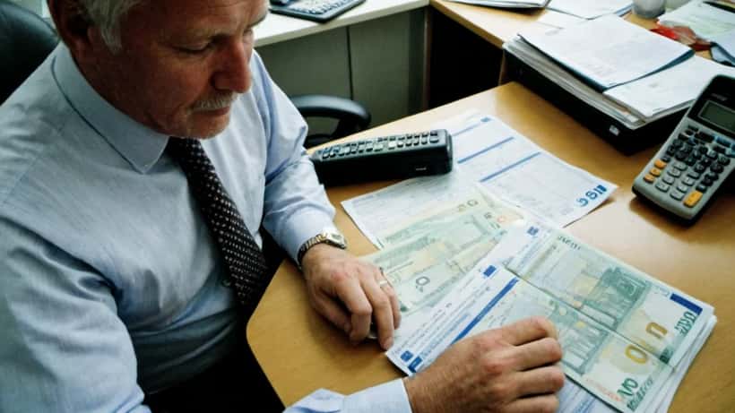 Norsk mann gjennomgår finansielle planleggingsdokumenter ved hjemmekontor med eurosedler på bordet