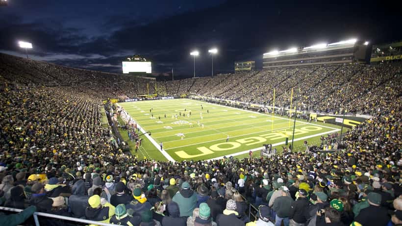 American football stadium lit up at night with packed crowd under stadium lights
