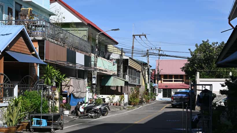 Gatescene i Thailand med parkerte scootere og husrekker under klart blå himmel