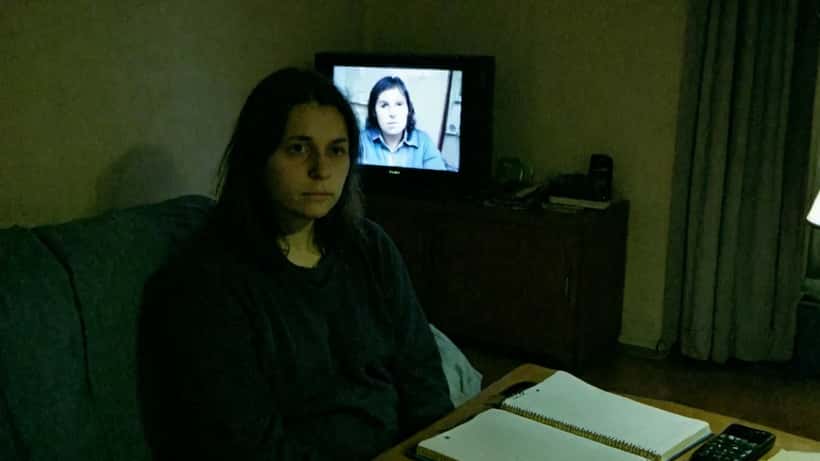 Femme regardant la télévision tard le soir dans un appartement parisien, visage éclairé par l'écran