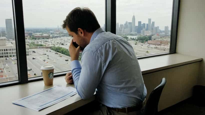 Professional man sitting alone at office desk looking stressed and pensive