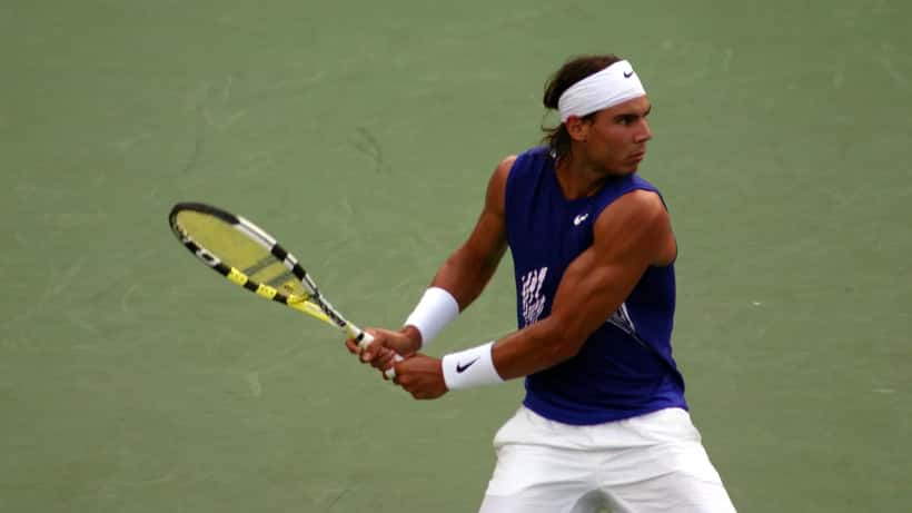 Rafael Nadal en action lors d'un match de tennis, illustrant sa carrière et sa reconversion entrepreneuriale réussie