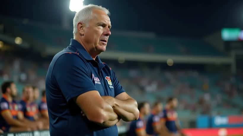 NRL head coach standing at the stadium sideline under floodlights, watching play intensely during an evening match