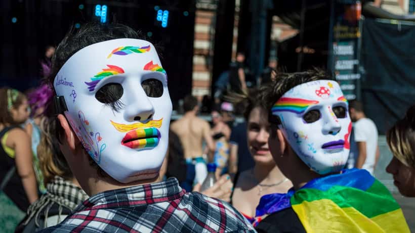 Pride parade participants marching with colorful rainbow flags and banners at a gay pride event