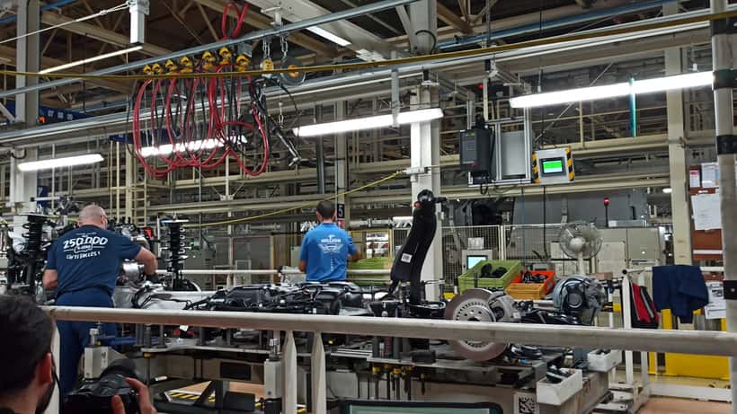 Catena di montaggio Stellantis con operai in tuta da lavoro