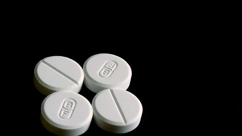 Paracetamol tablets and medication packaging on white surface, close-up