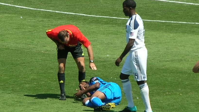 Fußballspieler liegt verletzt auf dem Rasen während eines Spiels