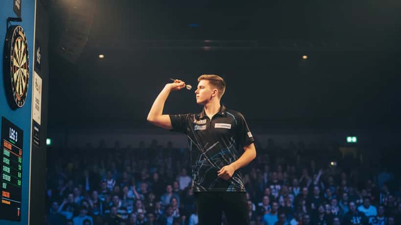 Jonge dartsspeler in arena onder spotlights, sportcompetitie Nederland