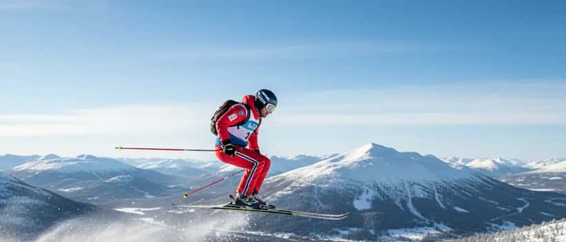 Norsk skihopper i lufta over snødekt fjellandskap under ski flying konkurranse