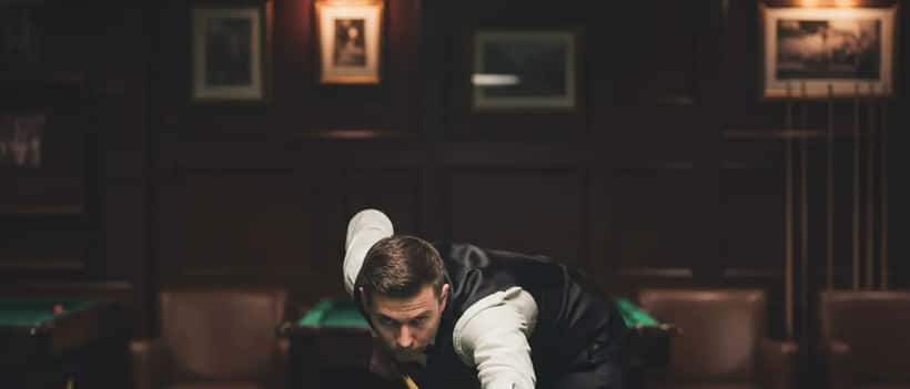 Snooker player demonstrating the forward spinal flexion and neck extension position that creates physical strain during competitive play