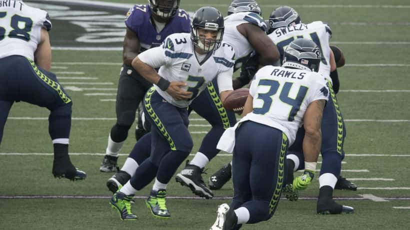 Russell Wilson lanzando el balón en un partido de la NFL durante su carrera con los Seattle Seahawks