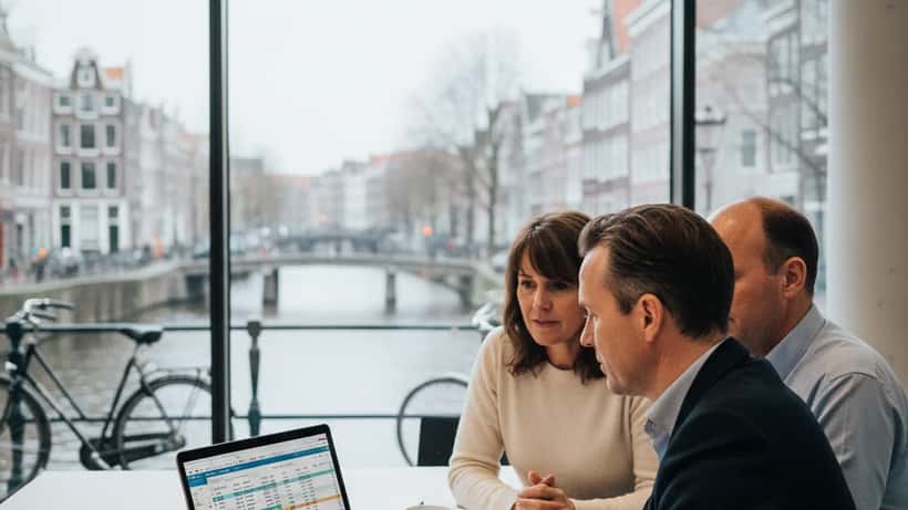 Financieel adviseur bespreekt budget en pensioenstrategie met cliënten in een Amsterdams kantoor