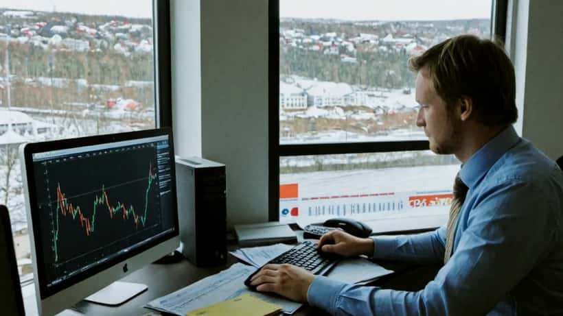 Finansrådgiver i Oslo-kontor med valutakursgrafer på skjerm
