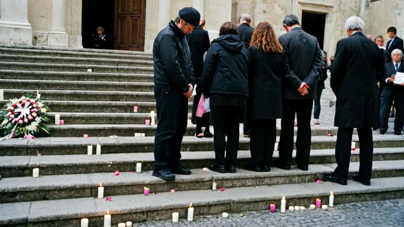Cérémonie funèbre devant une cathédrale à Nice, fleurs roses et blanches sur les marches
