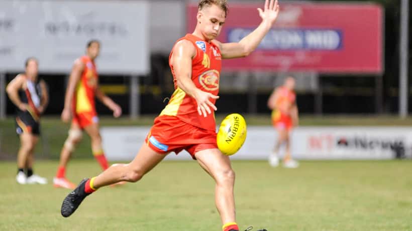 Will Brodie kicking a football during an AFL match