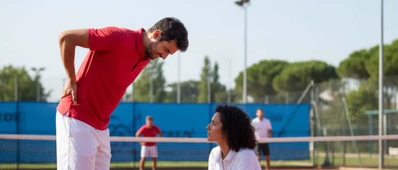 Tennista con dolore alla schiena assistito da un medico sportivo a bordo campo