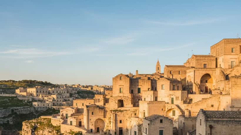 Veduta panoramica dei Sassi di Matera al tramonto durante la Pasqua 2026 con turisti che camminano tra le vie del centro storico UNESCO