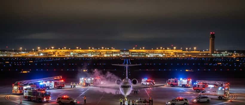 Emergency vehicles surrounding a regional jet on LaGuardia Airport runway at night