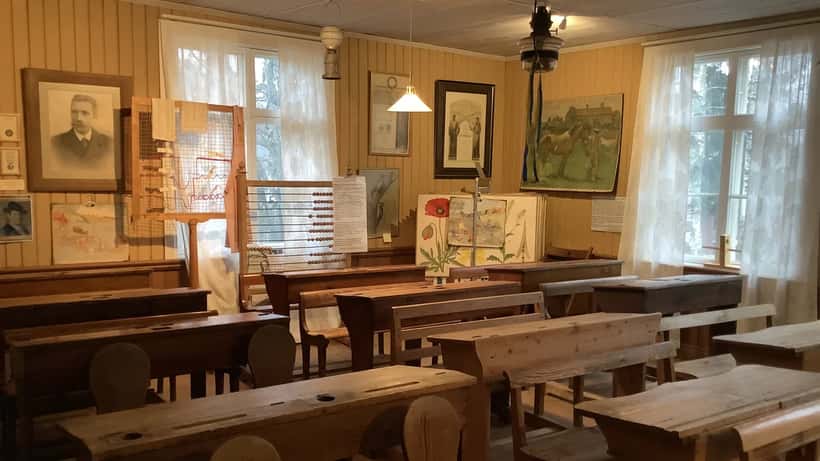 Klassrum i äldre svensk skolbyggnad med träbänkar och krittavla