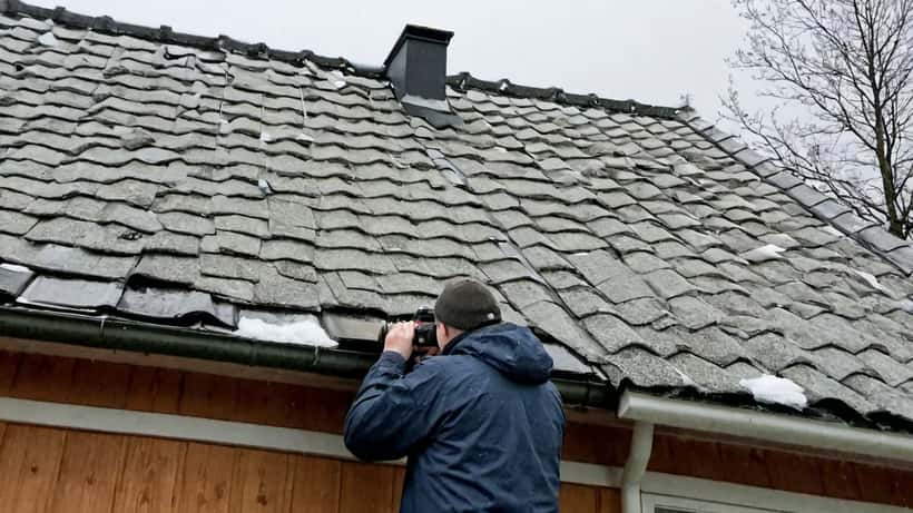 Boligeier undersøker løse takstein på hustak etter storm i Norge