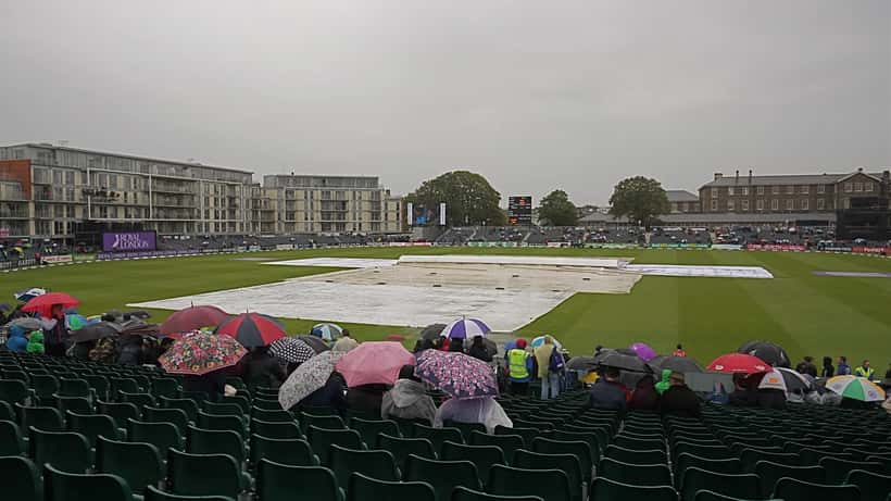 Rain-covered cricket ground in England with grey clouds overhead